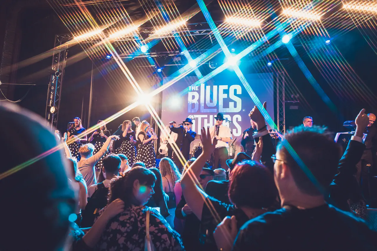 The Blues Others' full line-up and backing singers performing to a dancing crowd